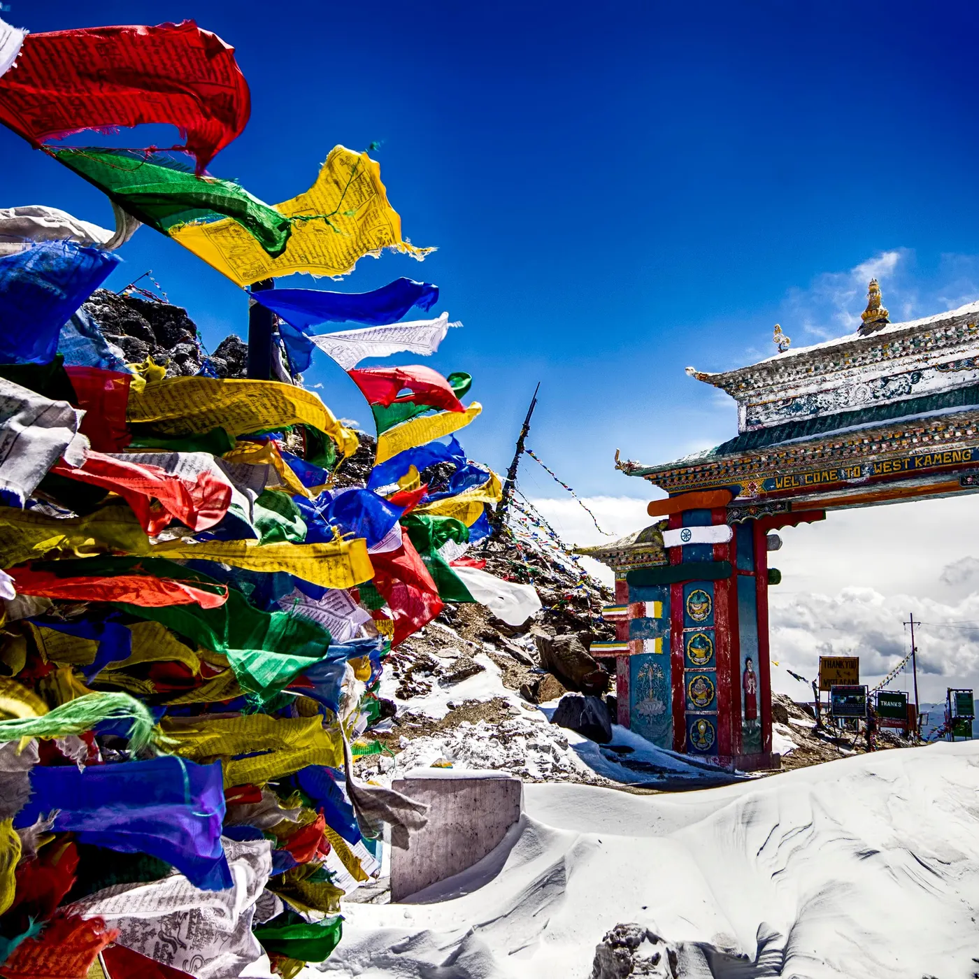 Prayer flags beside a painted monastery gate in the snow